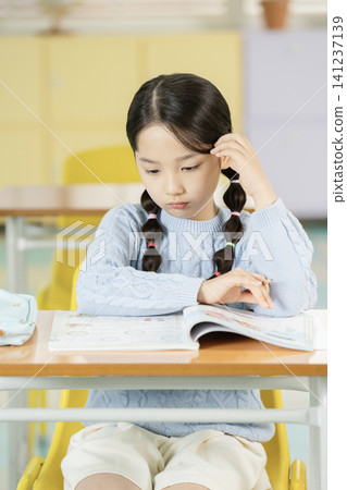 Schoolgirl with backpack smiling in a bright classroom Schoolgirl with backpack smiling in a bright classroom 141237139