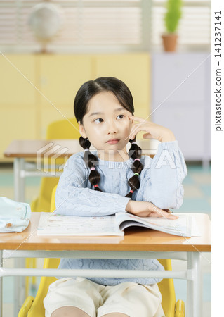 Elementary student writing in a textbook at her desk Elementary student writing in a textbook at her desk 141237141