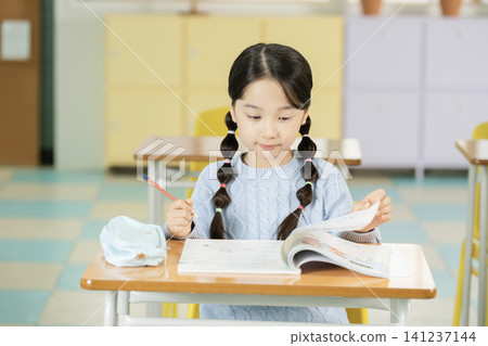 Schoolgirl with backpack smiling in a bright classroom Schoolgirl with backpack smiling in a bright classroom 141237144