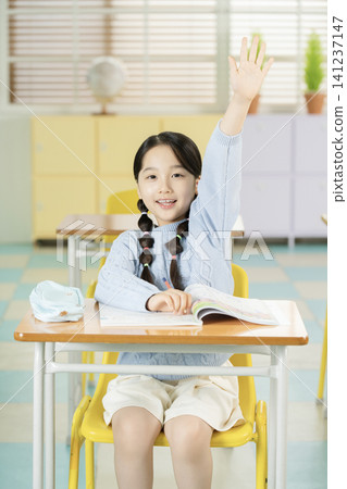 Elementary student writing in a textbook at her desk 141237147