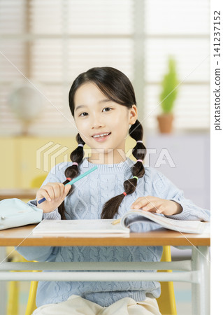 Schoolgirl with backpack smiling in a bright classroom 141237152