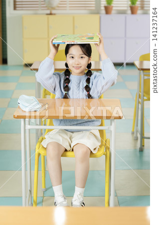 Schoolgirl with backpack smiling in a bright classroom Schoolgirl with backpack smiling in a bright classroom 141237164