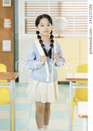 Elementary student writing in a textbook at her desk 141237166