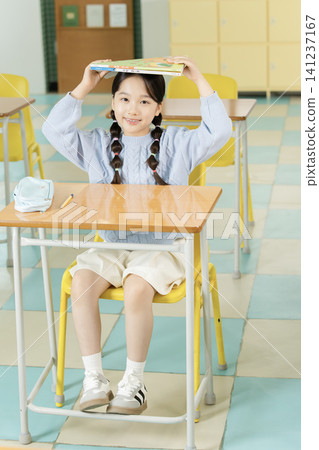Young schoolgirl raising her hand while studying in class Young schoolgirl raising her hand while studying in class 141237167