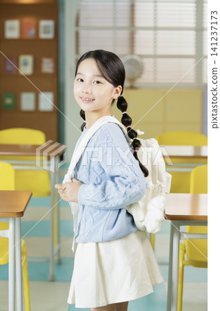 Young schoolgirl raising her hand while studying in class Young schoolgirl raising her hand while studying in class 141237173