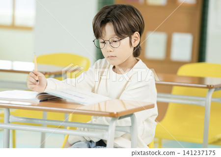 Boy studying quietly in a bright elementary classroom Boy studying quietly in a bright elementary classroom 141237175