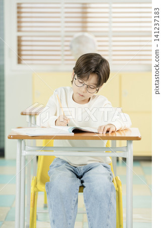 Elementary student with glasses reading during class Elementary student with glasses reading during class 141237183