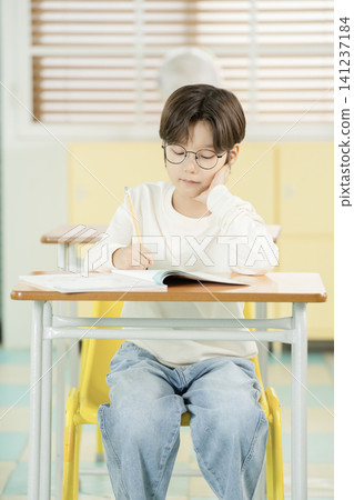 Boy studying quietly in a bright elementary classroom Boy studying quietly in a bright elementary classroom 141237184