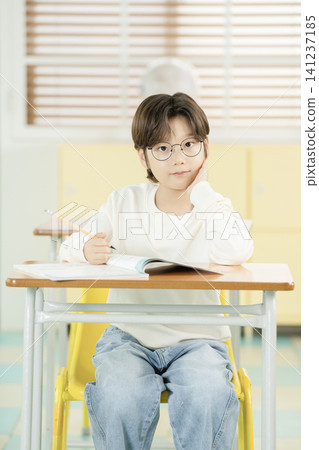Asian elementary schoolboy with glasses studying in a classroom Asian elementary schoolboy with glasses studying in a classroom 141237185