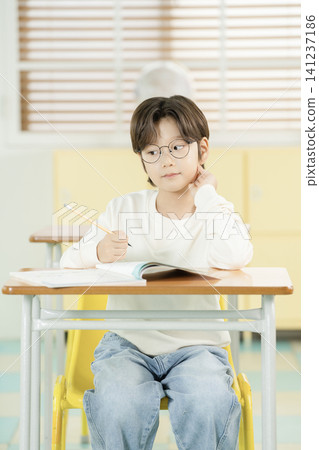 Young schoolboy writing in a textbook at a classroom desk 141237186
