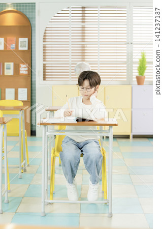 Elementary student with glasses reading during class Elementary student with glasses reading during class 141237187