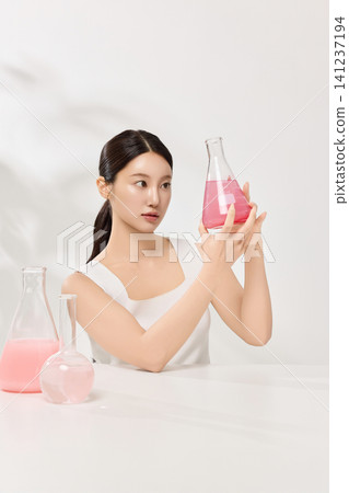 Asian woman posing with laboratory glassware and pink beauty serum Asian woman posing with laboratory glassware and pink beauty serum 141237194