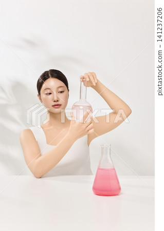 Woman examining cosmetic ingredients in flasks for a skincare concept Woman examining cosmetic ingredients in flasks for a skincare concept 141237206