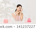 Asian woman posing with laboratory glassware and pink beauty serum 141237227