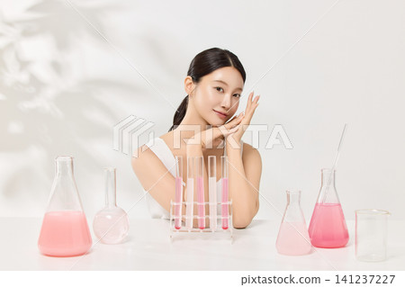 Asian woman posing with laboratory glassware and pink beauty serum Asian woman posing with laboratory glassware and pink beauty serum 141237227
