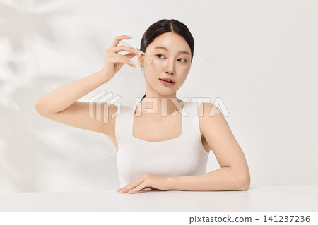 Young Asian woman holding an amber skincare serum bottle Young Asian woman holding an amber skincare serum bottle 141237236