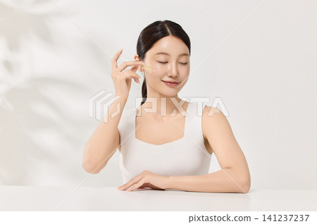 Beauty model posing with a brown cosmetic bottle in a clean studio Beauty model posing with a brown cosmetic bottle in a clean studio 141237237