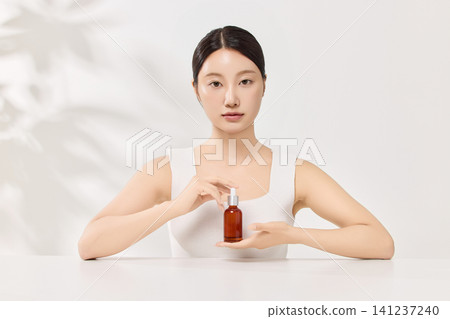Young Asian woman holding an amber skincare serum bottle 141237240
