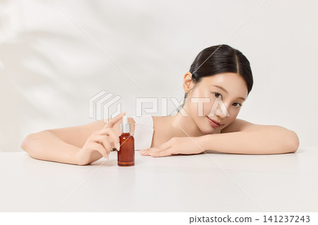 Young Asian woman holding an amber skincare serum bottle Young Asian woman holding an amber skincare serum bottle 141237243