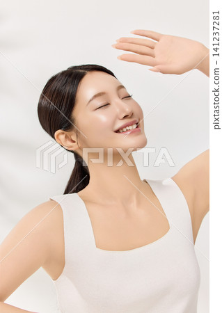 Young Asian woman applying skincare cream to her cheek Young Asian woman applying skincare cream to her cheek 141237281