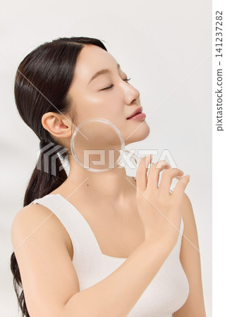 Beauty model using a facial massage tool in a clean studio 141237282