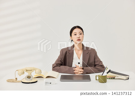 Asian businesswoman working at a white office desk with a laptop Asian businesswoman working at a white office desk with a laptop 141237312