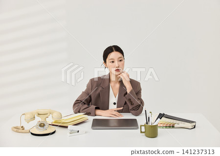 Professional woman talking on a vintage telephone at her desk Professional woman talking on a vintage telephone at her desk 141237313