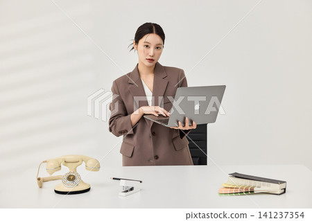 Businesswoman presenting a laptop in a bright minimalist office Businesswoman presenting a laptop in a bright minimalist office 141237354