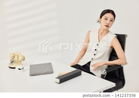 Asian businesswoman working at a white office desk with a laptop Asian businesswoman working at a white office desk with a laptop 141237356