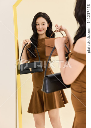 Woman styling a brown dress with a coat and handbag Woman styling a brown dress with a coat and handbag 141237458