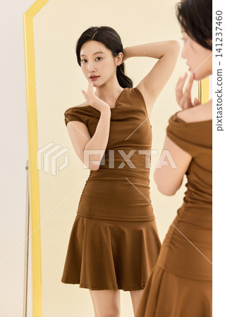 Young Asian woman checking her outfit in a full-length mirror 141237460
