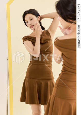 Fashionable woman choosing handbags in front of a mirror Fashionable woman choosing handbags in front of a mirror 141237461