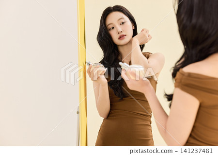 Young Asian woman checking her outfit in a full-length mirror Young Asian woman checking her outfit in a full-length mirror 141237481