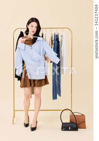 Fashion model selecting outfits on a clothing rack Fashion model selecting outfits on a clothing rack 141237484