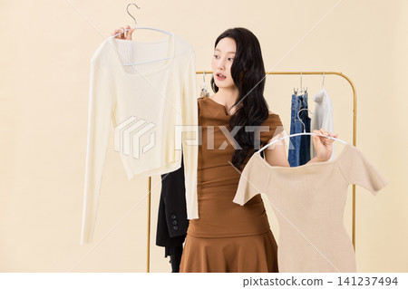 Fashion model selecting outfits on a clothing rack 141237494