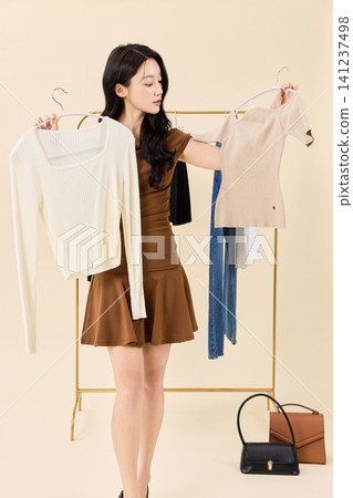 Young Asian woman choosing clothes from a wardrobe rack 141237498