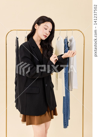 Fashion model selecting outfits on a clothing rack Fashion model selecting outfits on a clothing rack 141237502