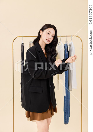 Young Asian woman choosing clothes from a wardrobe rack Young Asian woman choosing clothes from a wardrobe rack 141237503