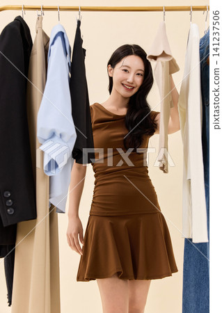 Fashion model selecting outfits on a clothing rack Fashion model selecting outfits on a clothing rack 141237506