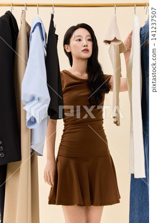 Young Asian woman choosing clothes from a wardrobe rack Young Asian woman choosing clothes from a wardrobe rack 141237507