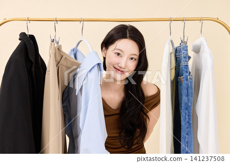 Young Asian woman choosing clothes from a wardrobe rack Young Asian woman choosing clothes from a wardrobe rack 141237508