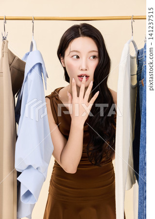 Fashion model selecting outfits on a clothing rack Fashion model selecting outfits on a clothing rack 141237515