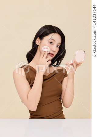 Woman checking her lips in a round handheld mirror Woman checking her lips in a round handheld mirror 141237544