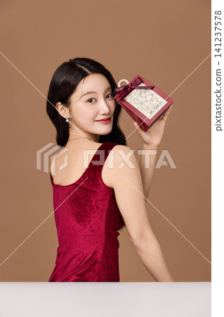 Holiday gift presentation with an elegant woman in a red dress Holiday gift presentation with an elegant woman in a red dress 141237578