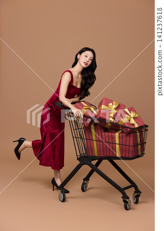 Asian woman pushing a shopping cart filled with wrapped gifts 141237618