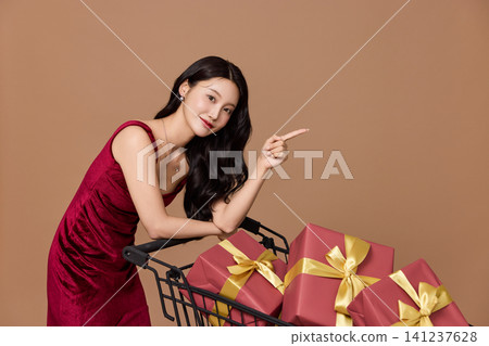 Asian woman pushing a shopping cart filled with wrapped gifts Asian woman pushing a shopping cart filled with wrapped gifts 141237628