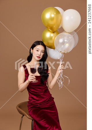 Asian woman in a red dress posing with party balloons Asian woman in a red dress posing with party balloons 141237668