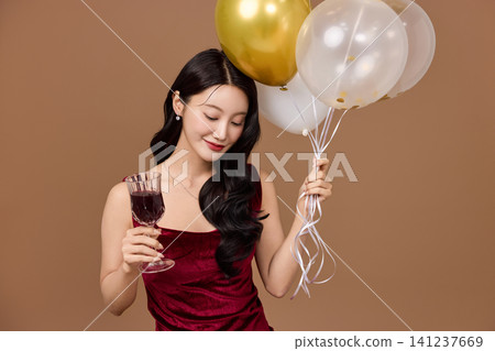 Elegant woman celebrating with balloons and a glass of wine Elegant woman celebrating with balloons and a glass of wine 141237669
