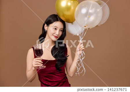 Asian woman in a red dress posing with party balloons Asian woman in a red dress posing with party balloons 141237671
