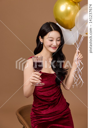 Elegant woman celebrating with balloons and a glass of wine Elegant woman celebrating with balloons and a glass of wine 141237674